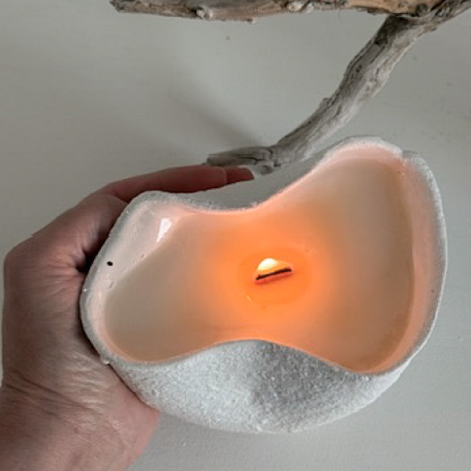 Handmade ceramic soy candle in a pinched, undulating vessel with a textured neutral finish, reusable after burning.