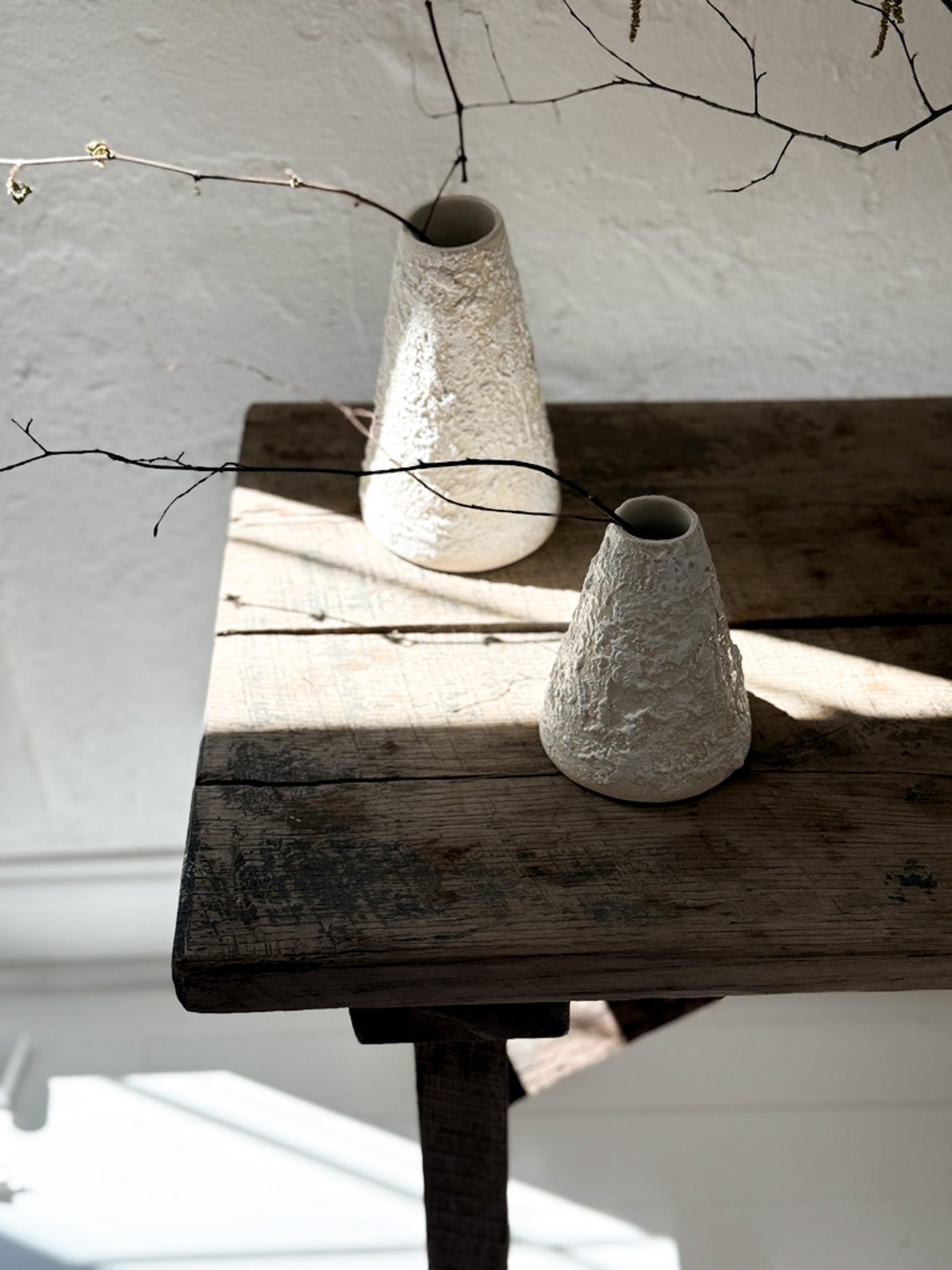 Two textured handmade Muddy Heart vases on a sunlit wooden table