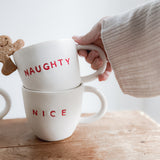 Handmade ceramic holiday mug lettered Naughty and Nice in a neutral glaze