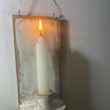 Handmade stoneware wall sconce holding a taper candle, hung from wire