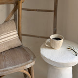Handmade ceramic mug with deep carved vertical lines and a textured neutral glaze.