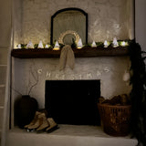 Handmade white stoneware tree luminaries with star cutouts glowing with LED tealight candles
