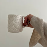 Handmade ceramic star mug held in hand, showing its wide, cozy form