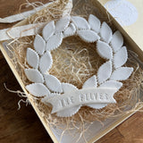 Personalized porcelain laurel wreath ornament with a gloss-white glaze and custom name on linen twine