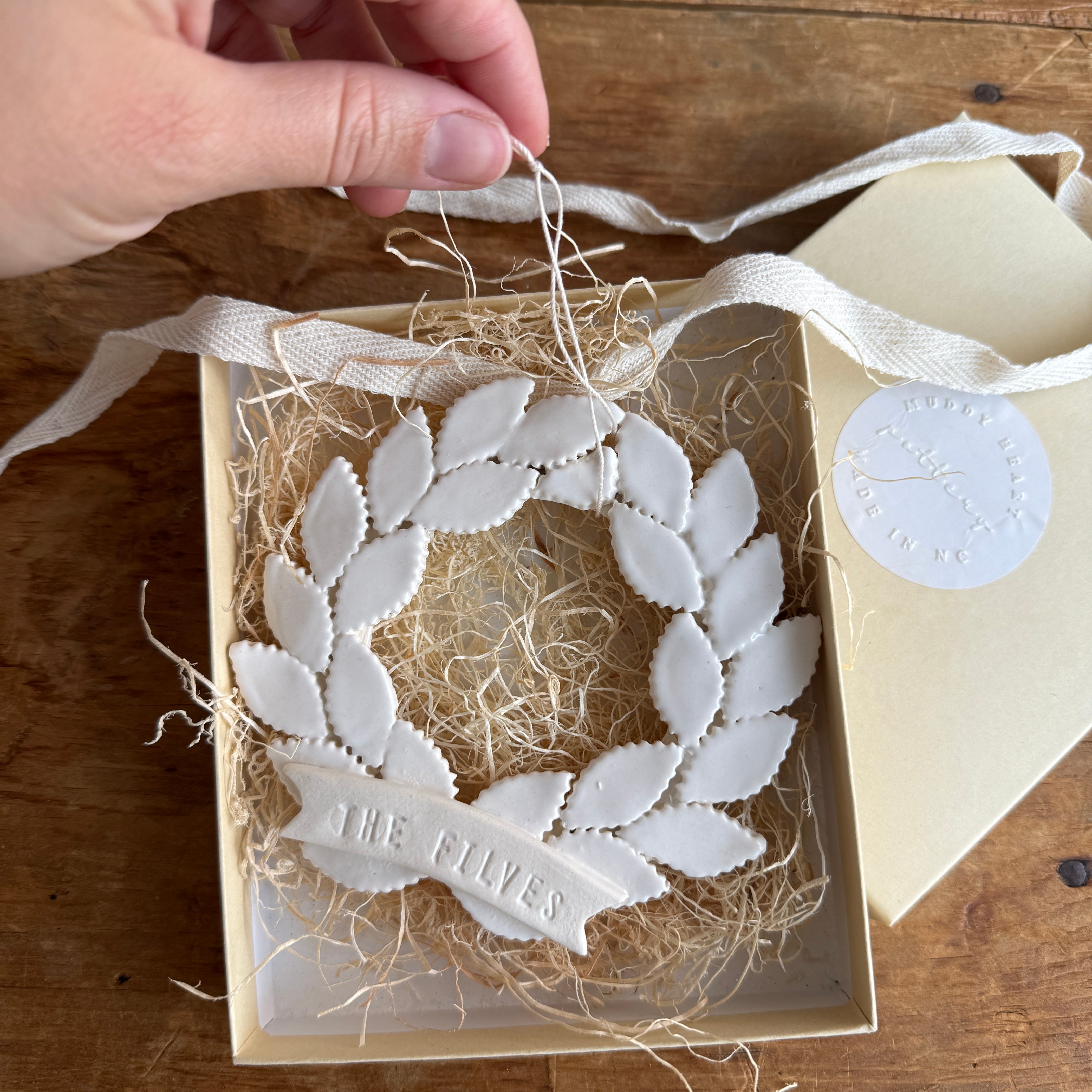 Personalized porcelain laurel wreath ornament with a gloss-white glaze and custom name on linen twine