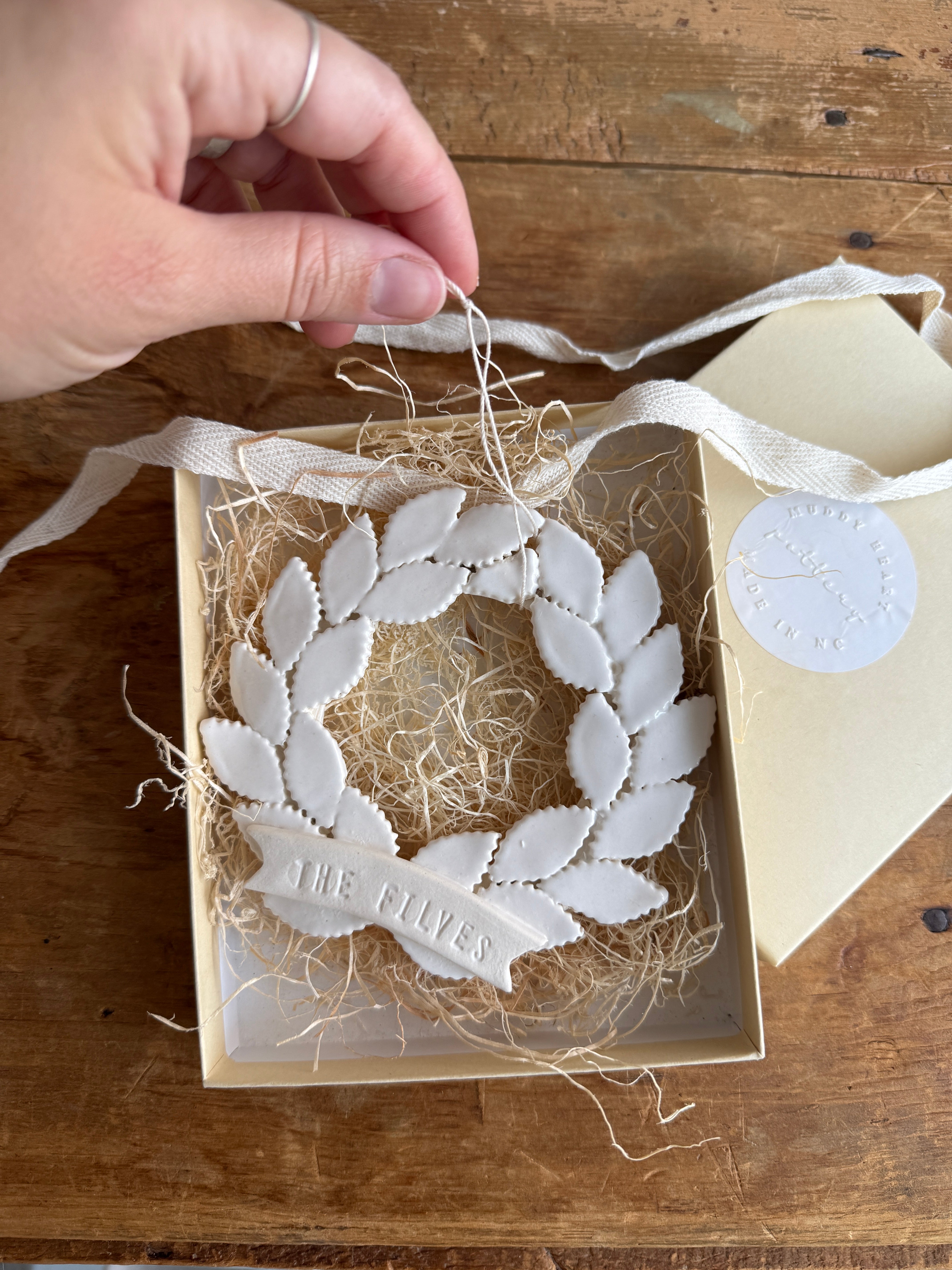 Personalized porcelain laurel wreath ornament with a gloss-white glaze and custom name on linen twine