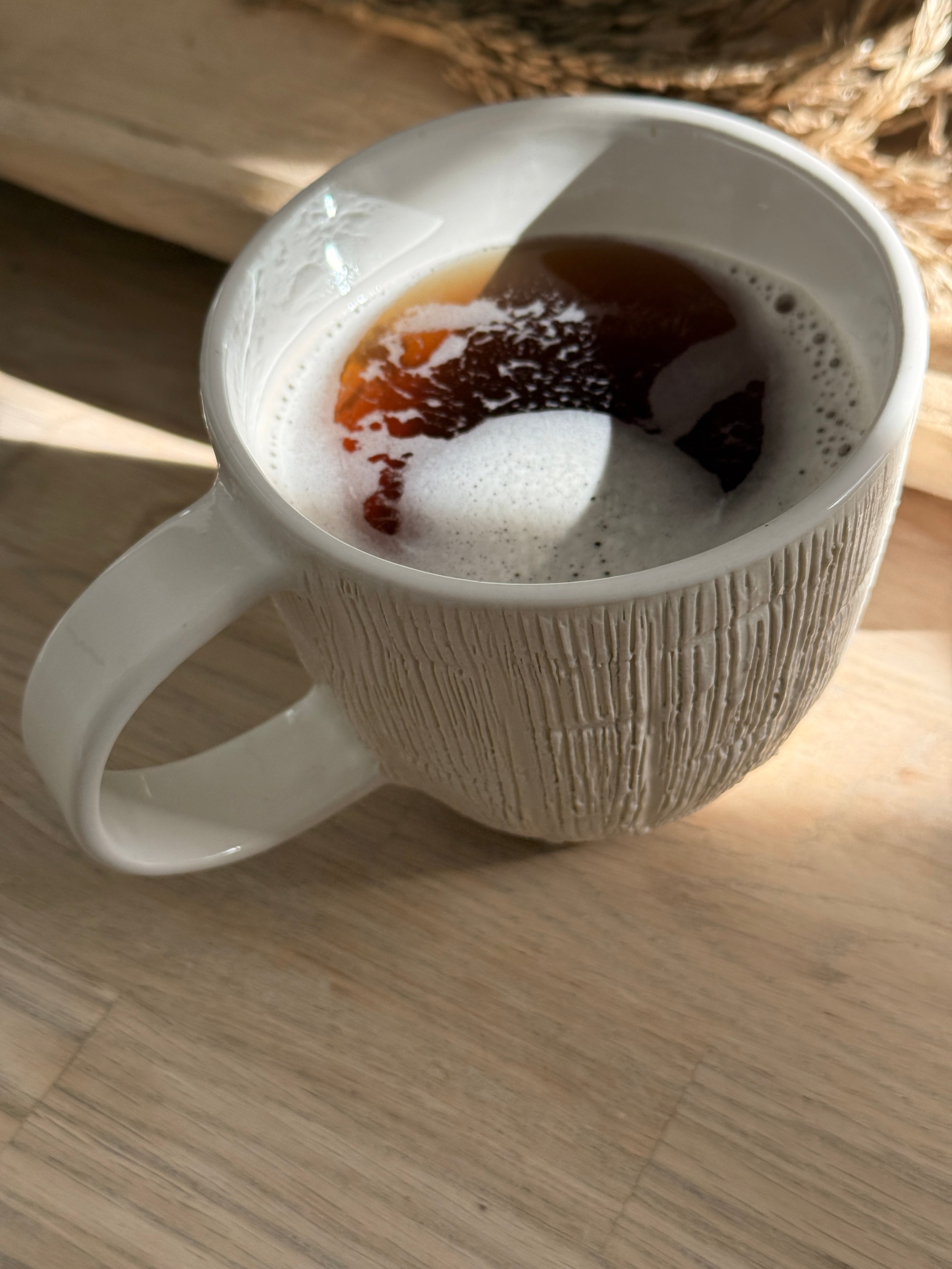Handmade ceramic mug with deep carved vertical lines and a textured neutral glaze.