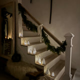 Handmade white stoneware tree luminaries with star cutouts glowing with LED tealight candles