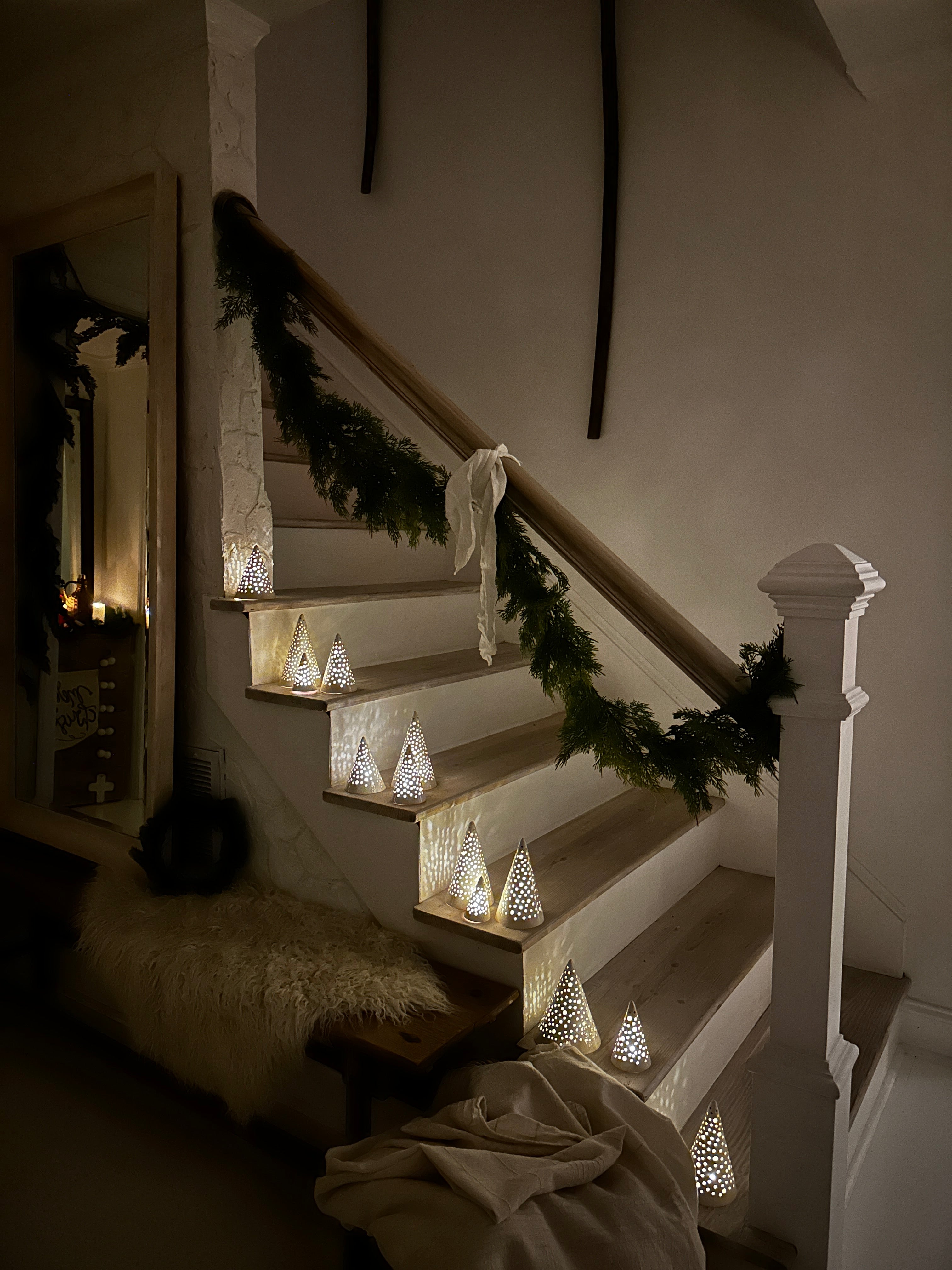 Handmade white stoneware tree luminaries with star cutouts glowing with LED tealight candles