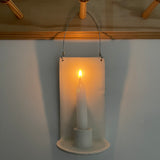 Handmade stoneware wall sconce holding a taper candle, hung from wire
