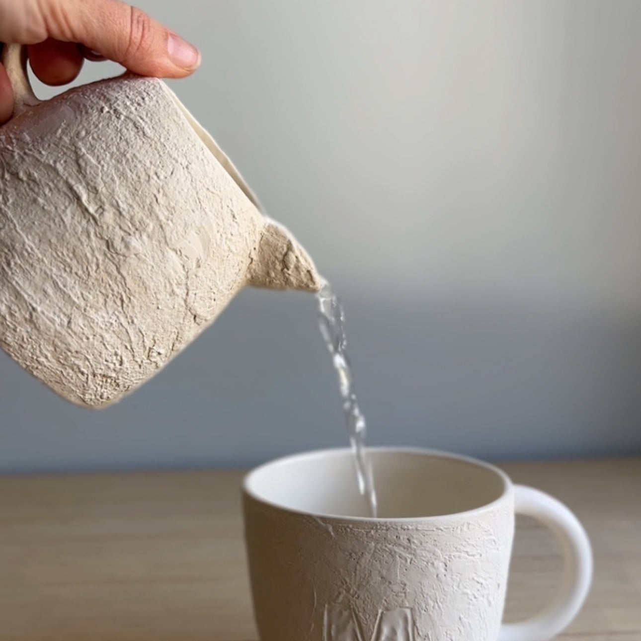 Handmade deep ceramic coffee mug with a textured exterior and personalized initial