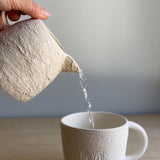 Handmade deep ceramic coffee mug with a textured exterior and personalized initial