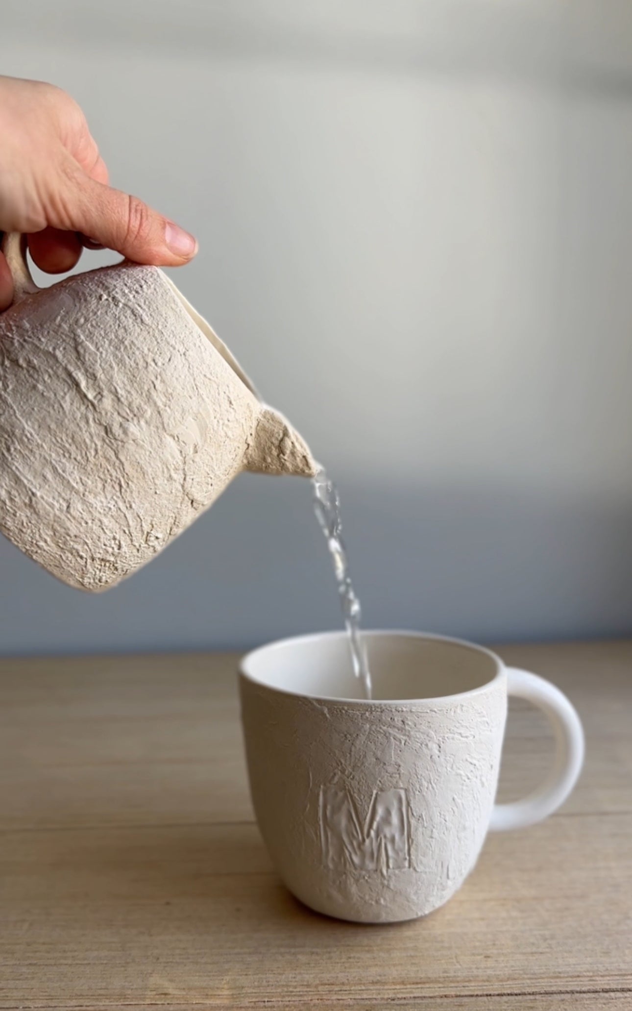 Handmade deep ceramic coffee mug with a textured exterior and personalized initial