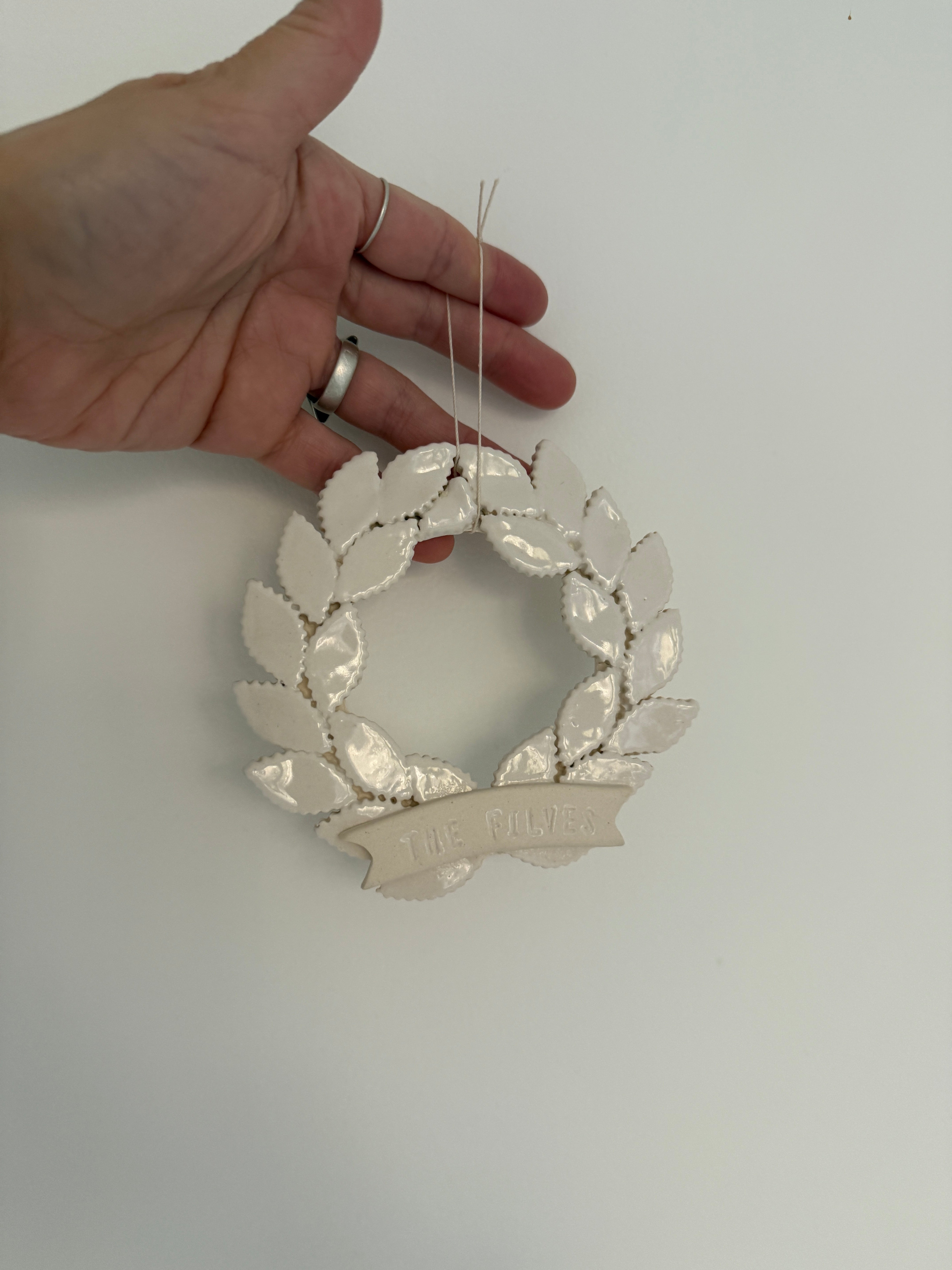 Personalized porcelain laurel wreath ornament with a gloss-white glaze and custom name on linen twine