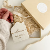 Personalized white porcelain house ornament hand-lettered with a name, hung on twine