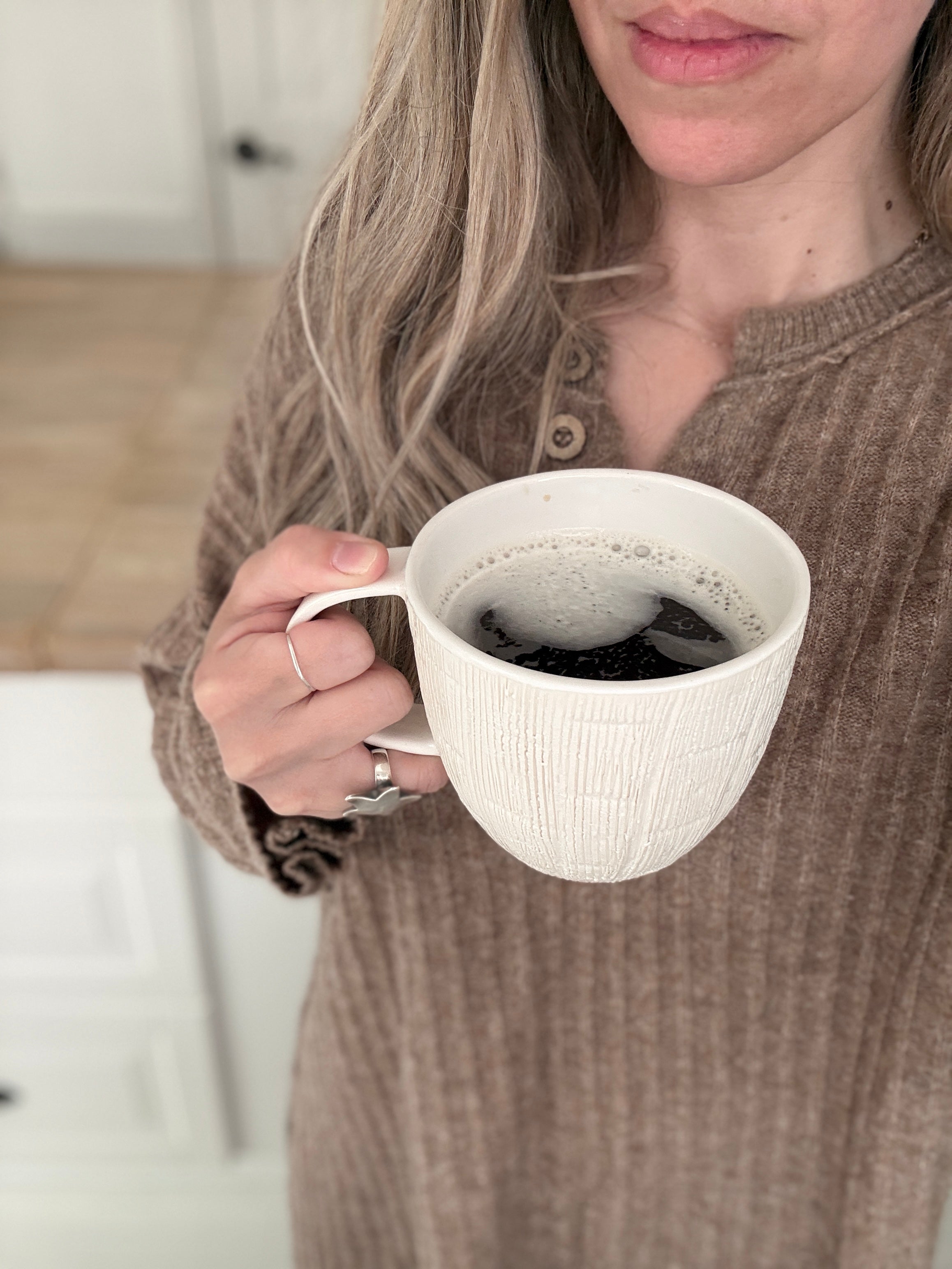 Handmade ceramic mug with deep carved vertical lines and a textured neutral glaze.