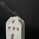Handmade ceramic cottage incense burner with smoke drifting from the chimney
