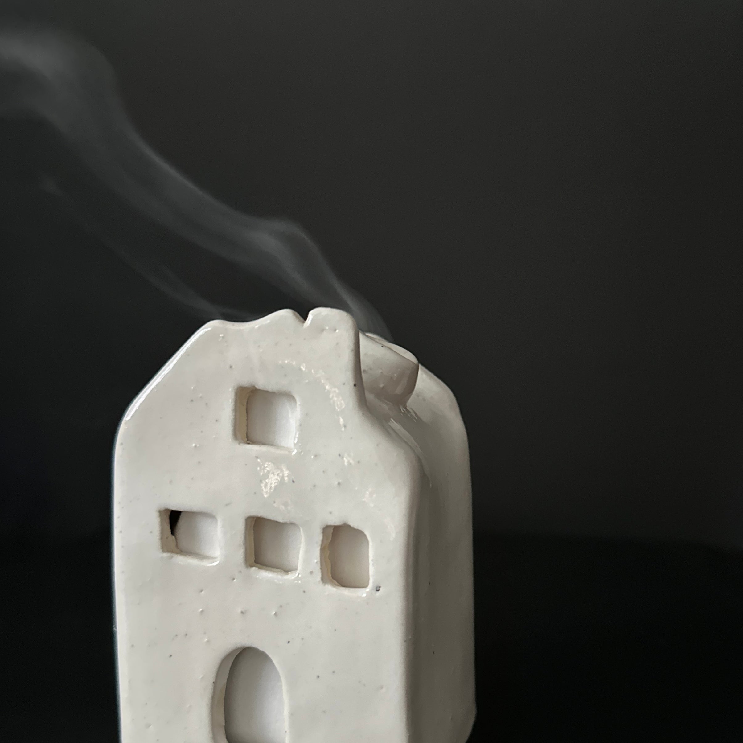Handmade ceramic cottage incense burner with smoke drifting from the chimney