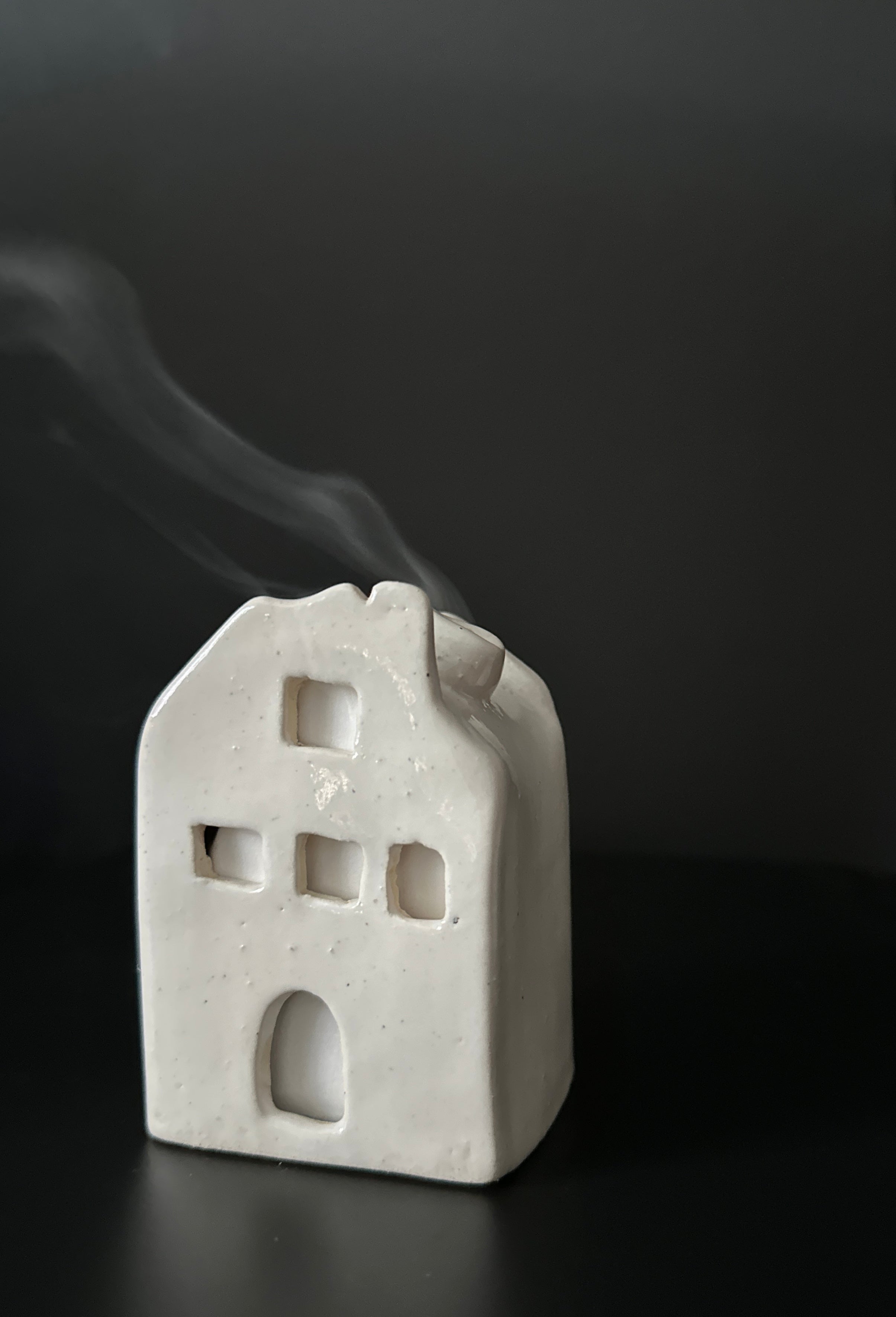 Handmade ceramic cottage incense burner with smoke drifting from the chimney