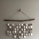 Neutral-colored ceramic disc wall hanging on driftwood