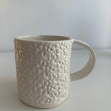 Close-up of the carved star texture on a handmade white ceramic mug