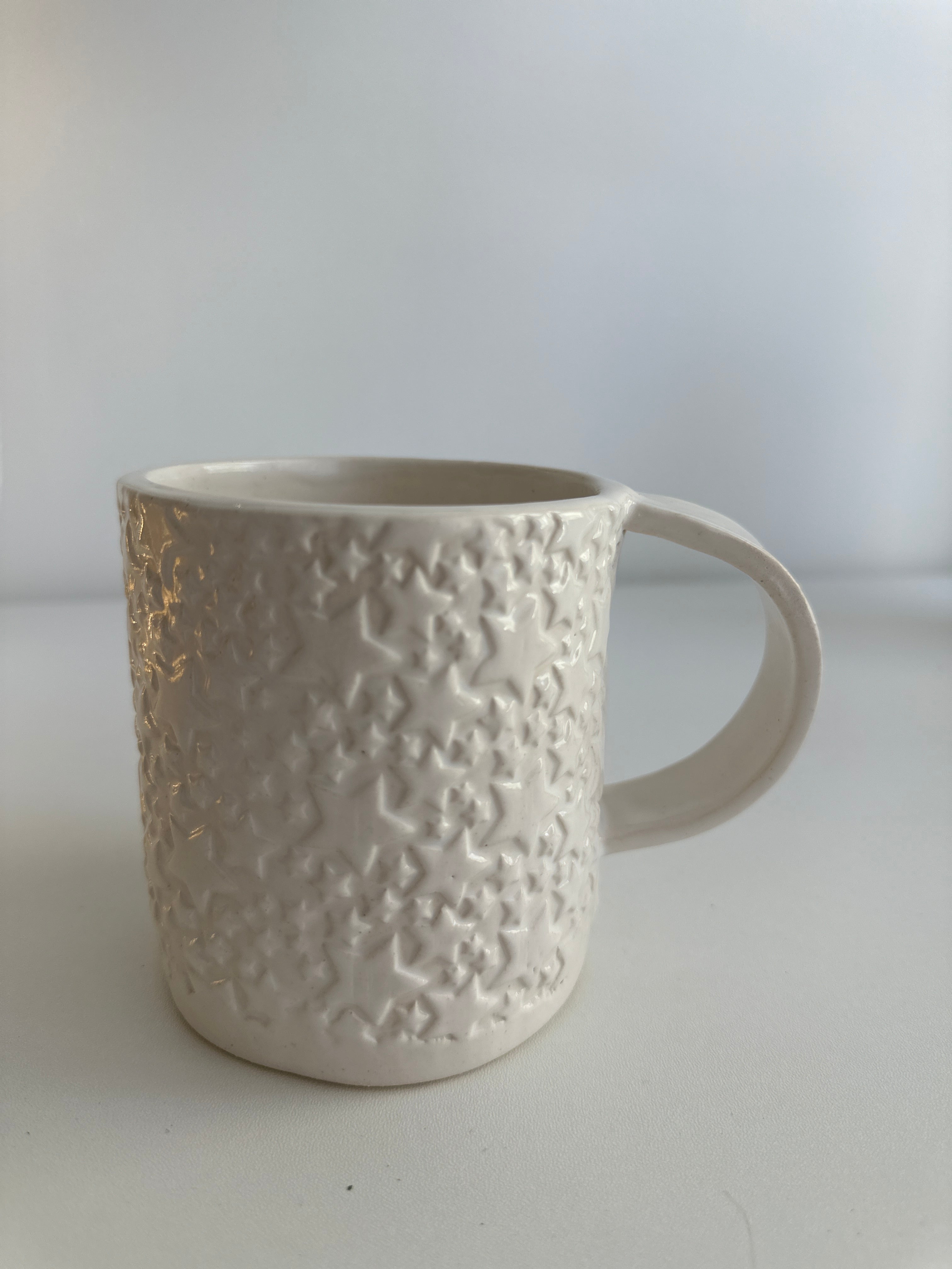 Close-up of the carved star texture on a handmade white ceramic mug