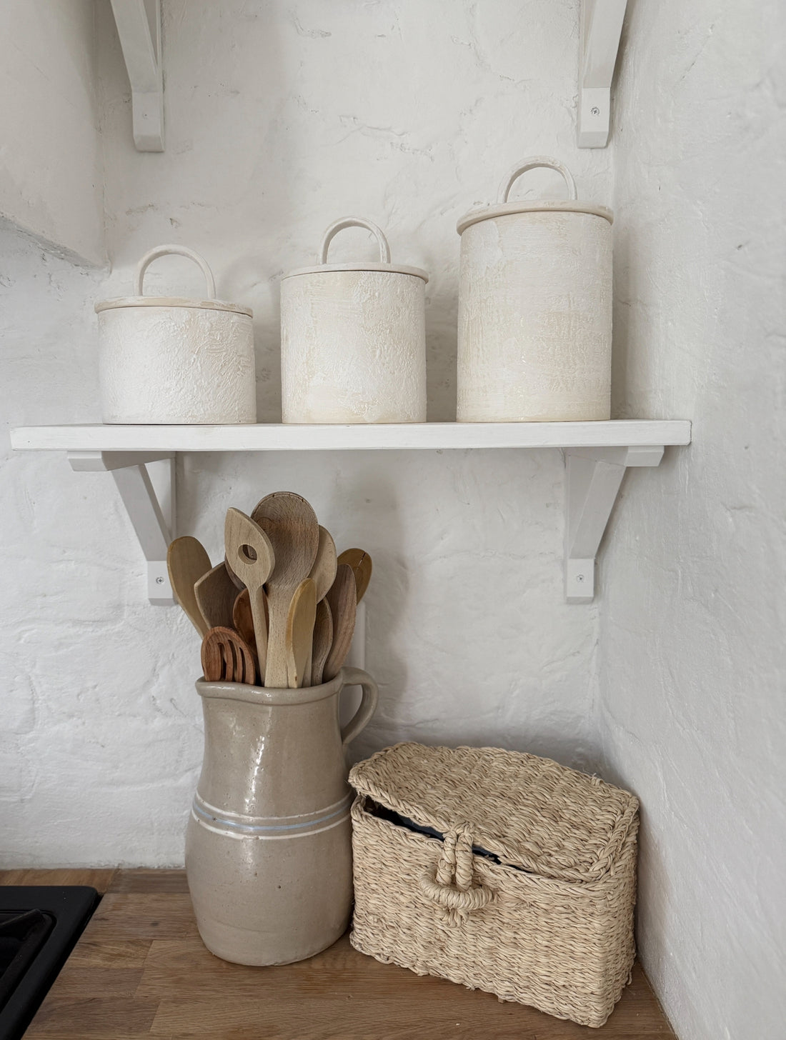 A styled grouping of handmade ceramic canisters on a shelf