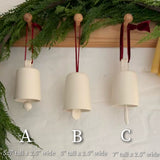Handmade ceramic holiday bell ornament with a white eggshell finish and red velvet ribbon