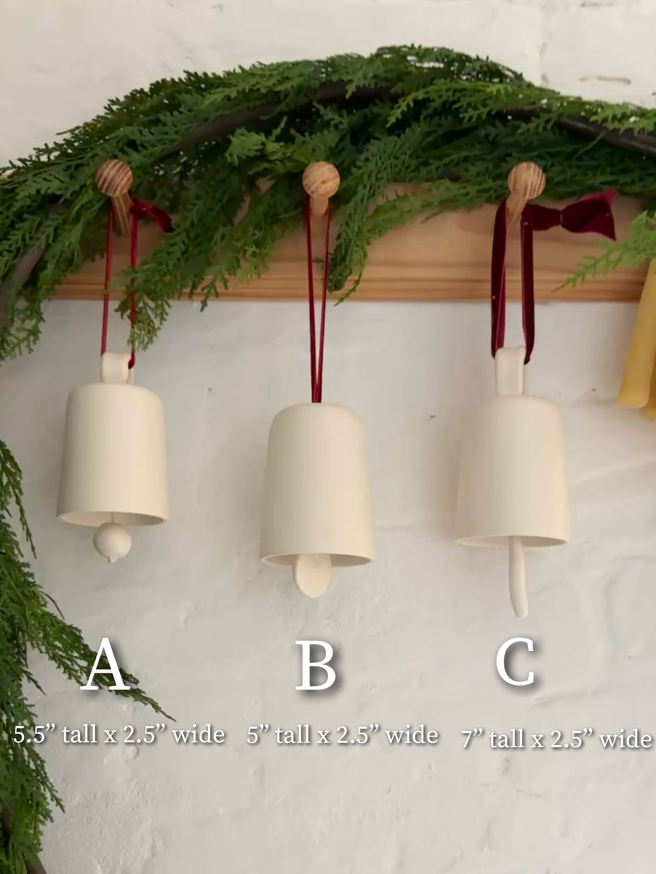 Handmade ceramic holiday bell ornament with a white eggshell finish and red velvet ribbon