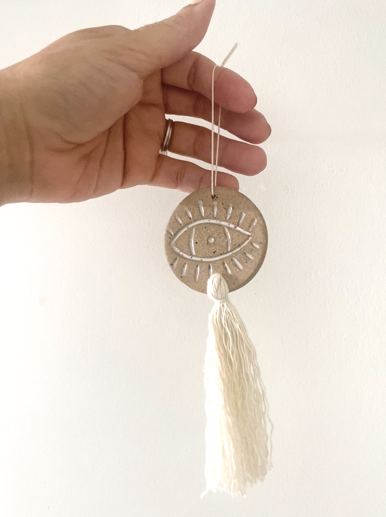 Handcrafted ceramic evil eye ornament with tassel, boho wall decor