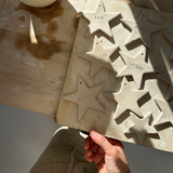 Close-up of a hand-lettered name on a white porcelain star ornament