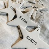 Small personalized porcelain star ornaments in white, shown as tree decorations
