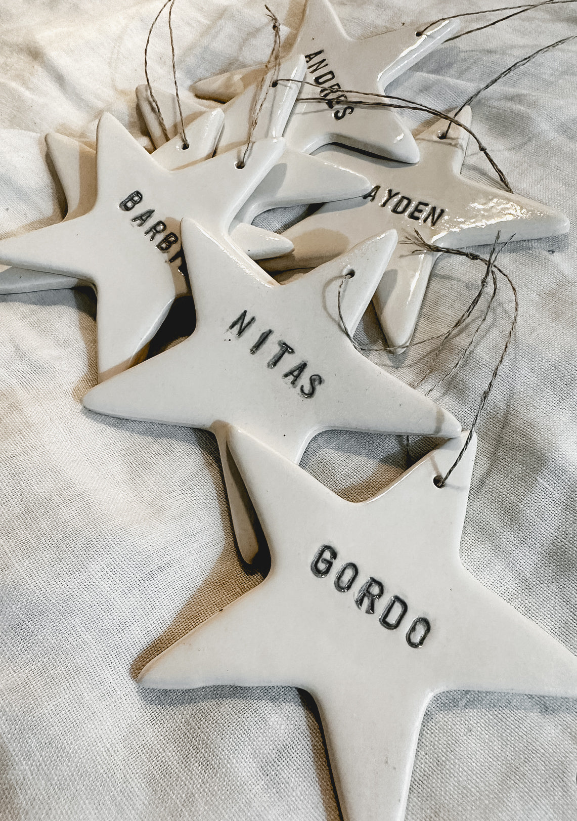 Small personalized porcelain star ornaments in white, shown as tree decorations