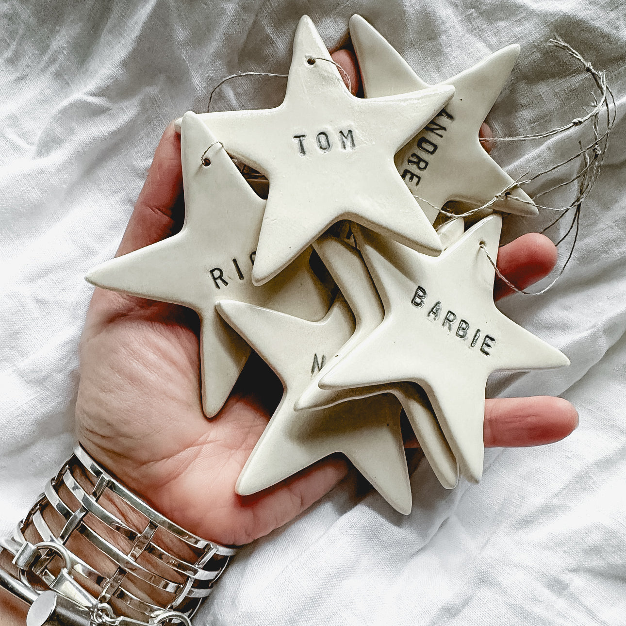 Personalized white porcelain star ornament on natural linen twine, hand-lettered with a name