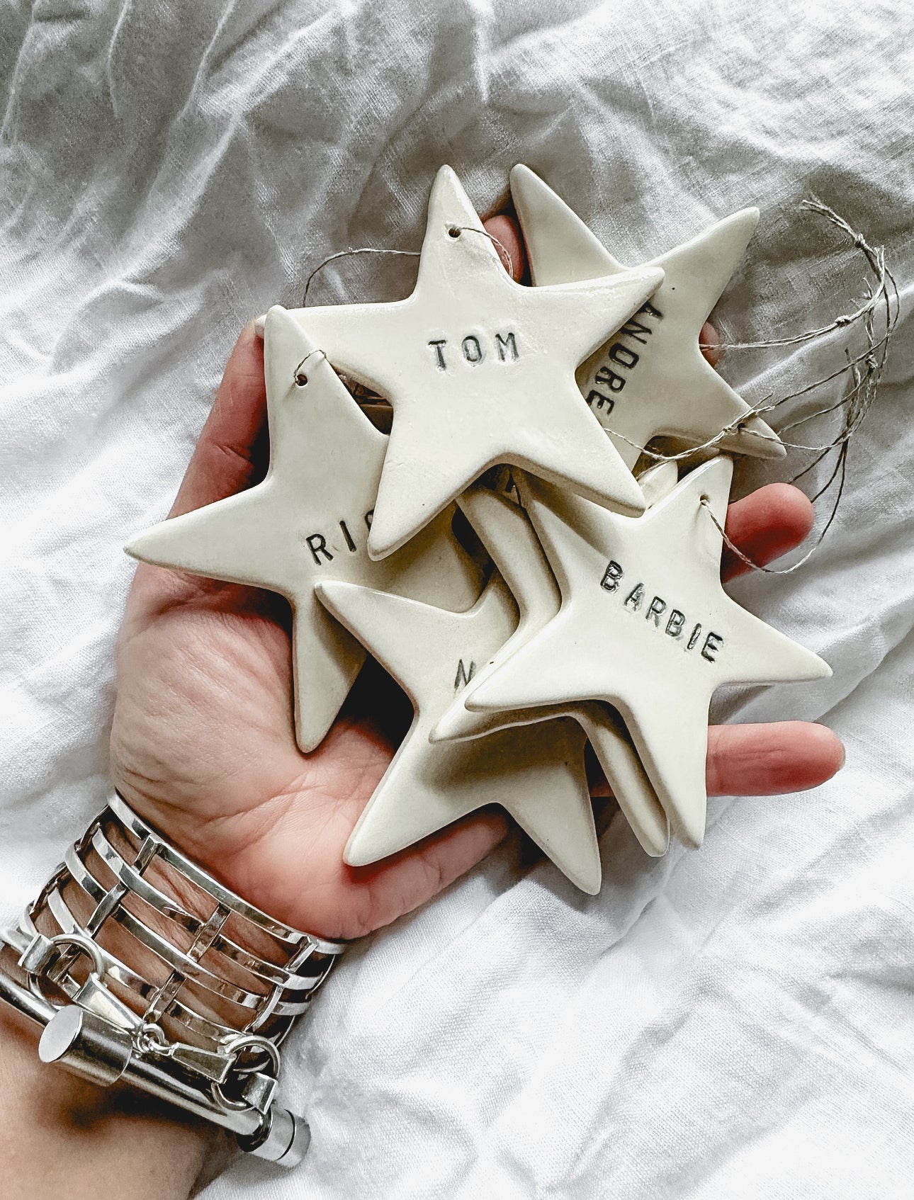 Personalized white porcelain star ornament on natural linen twine, hand-lettered with a name