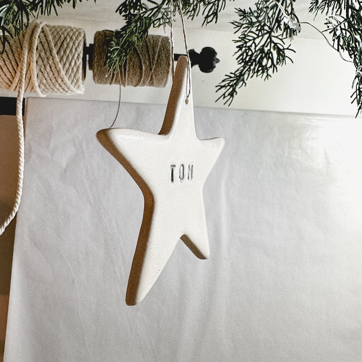Handmade porcelain star ornament tied with linen twine, personalized as a gift tag