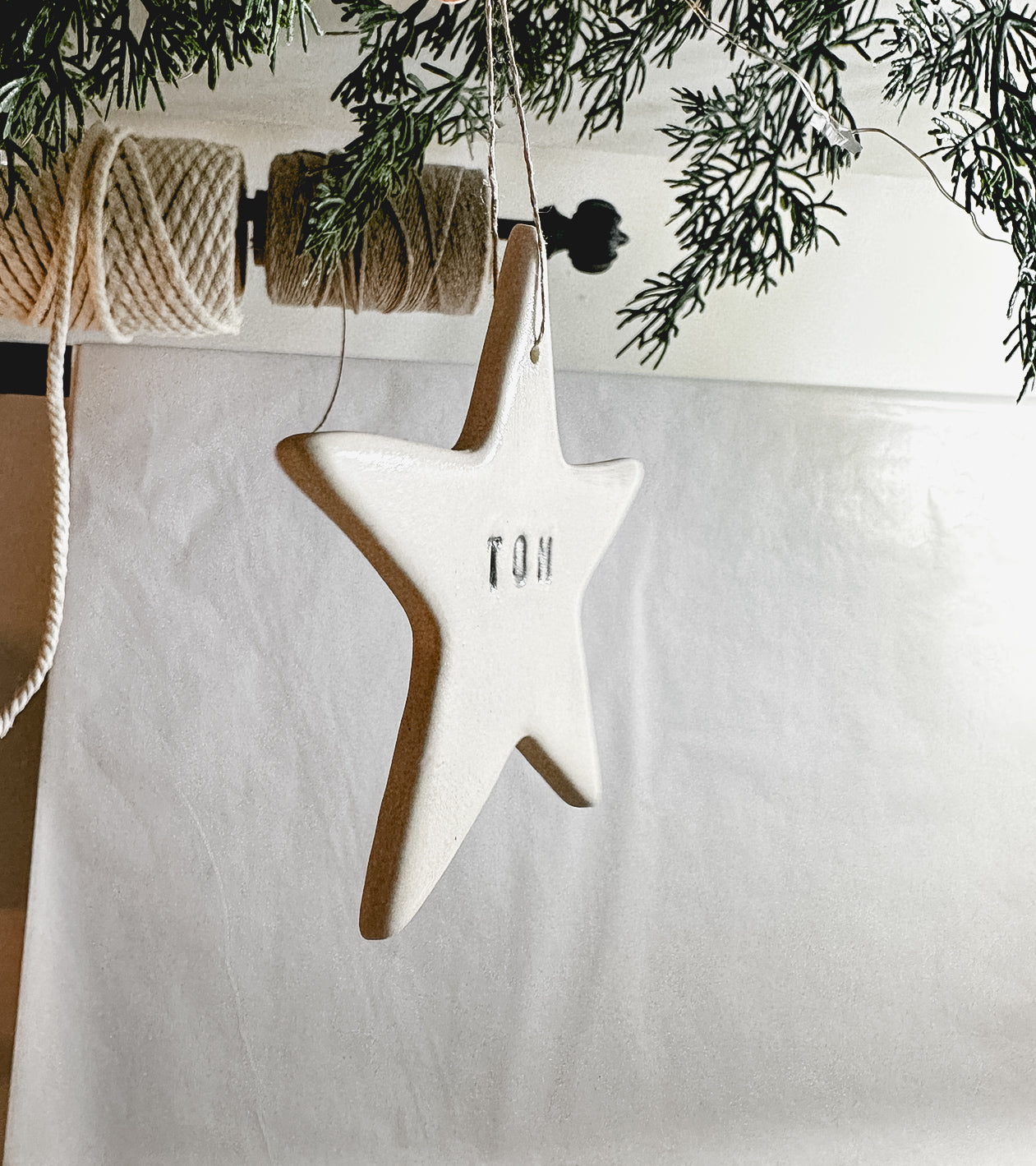 Handmade porcelain star ornament tied with linen twine, personalized as a gift tag