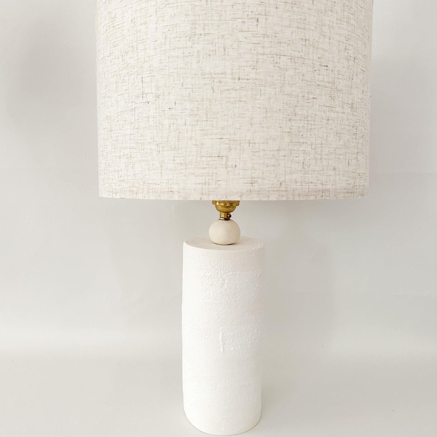 Handmade ceramic Wilma table lamp with a minimalist column base and linen shade