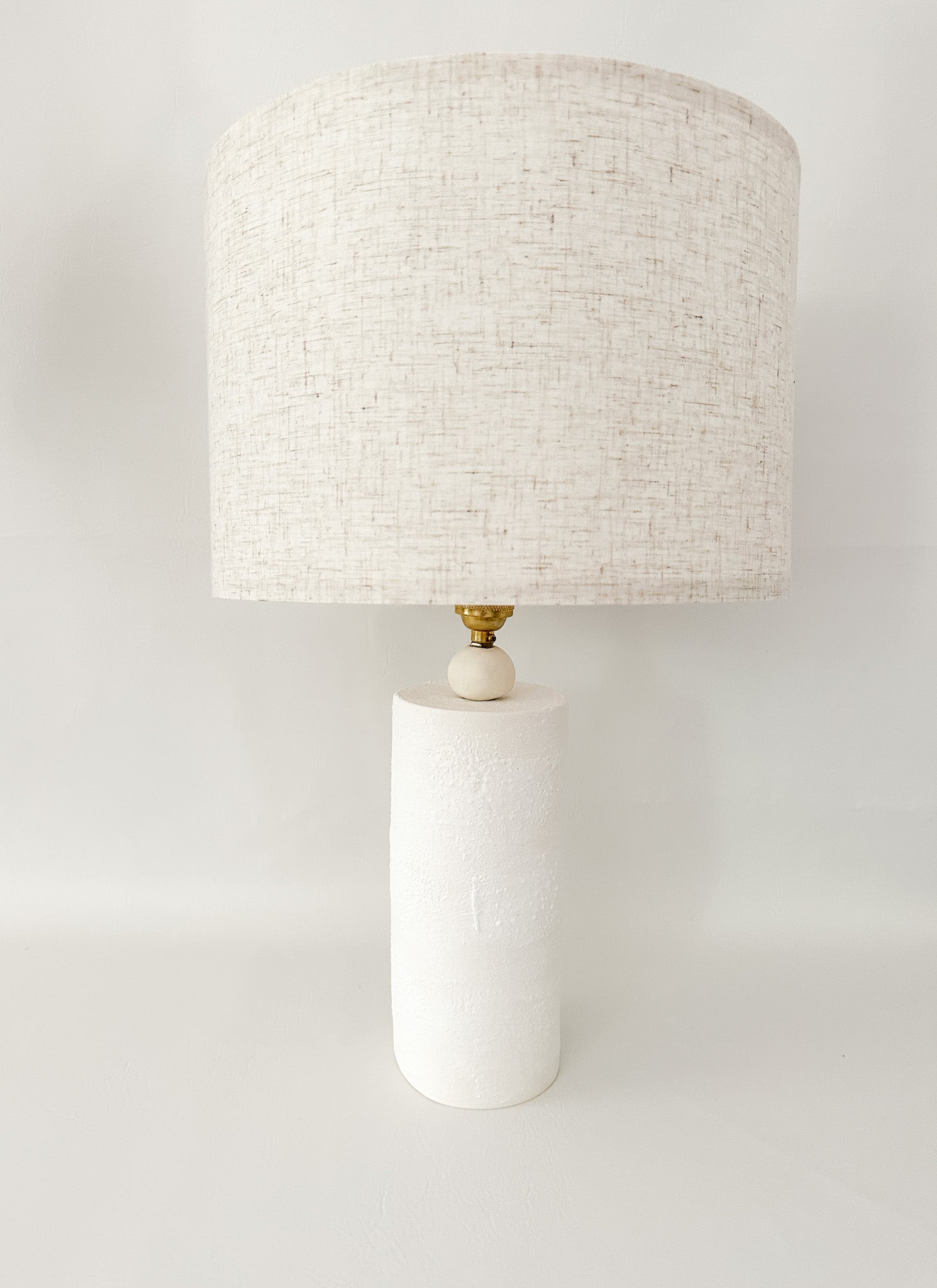 Handmade ceramic Wilma table lamp with a minimalist column base and linen shade