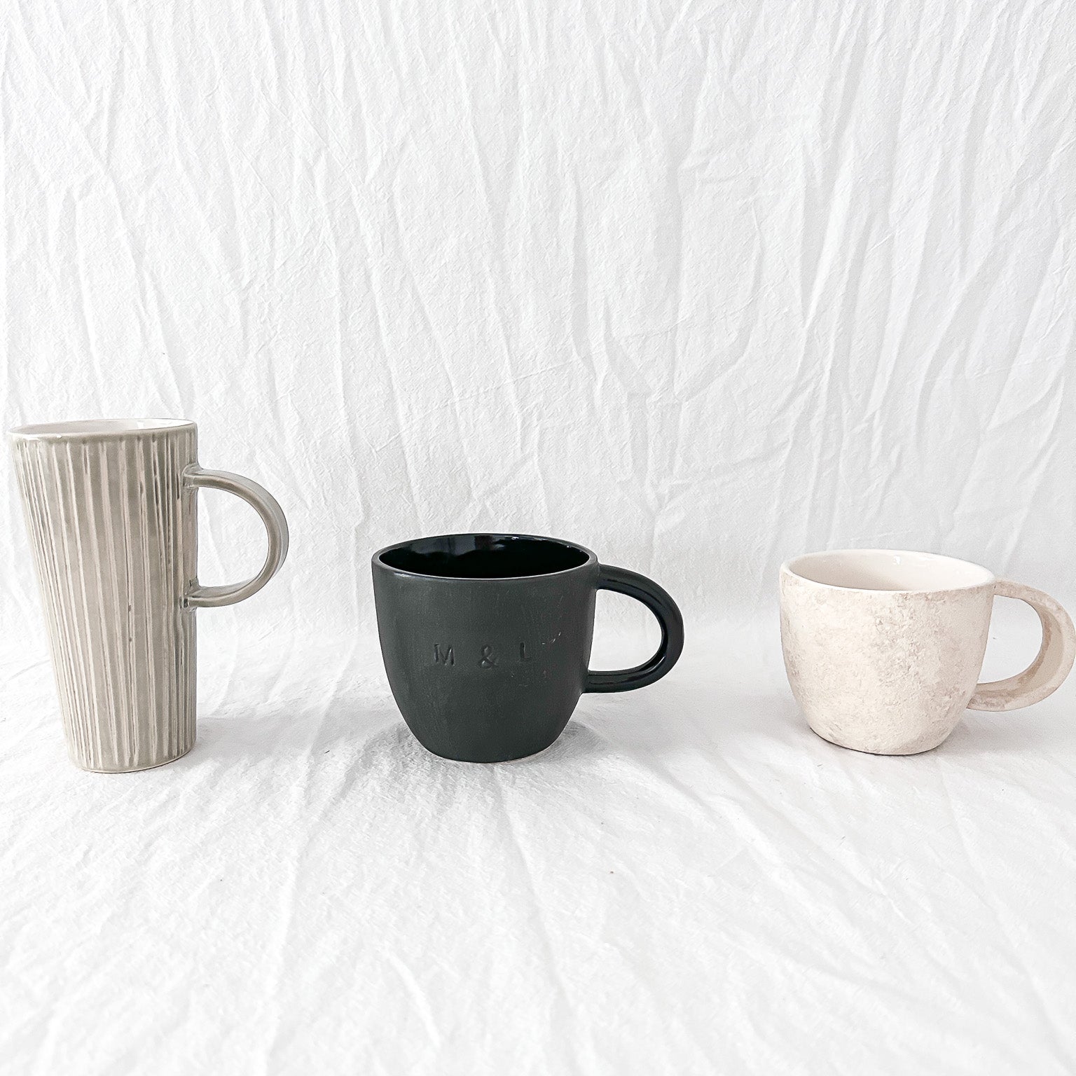 Assorted handmade ceramic mugs with textured glazes, dishwasher-safe seconds-sale pieces from Muddy Heart