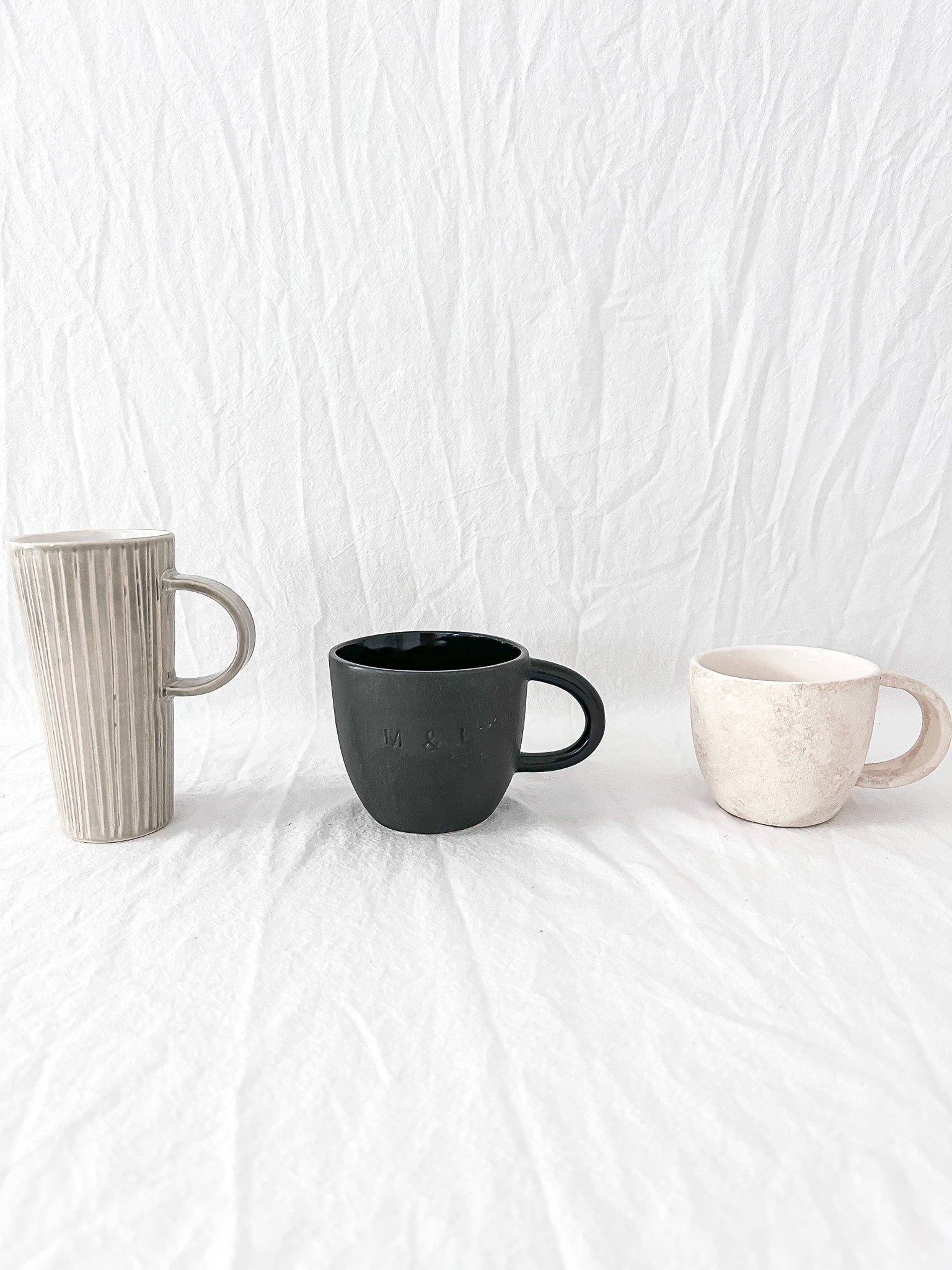 Assorted handmade ceramic mugs with textured glazes, dishwasher-safe seconds-sale pieces from Muddy Heart