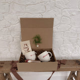 Pair of handmade ceramic mugs reading Naughty and Nice, paired with a hot cocoa and marshmallow mix.
