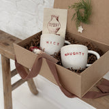 Pair of handmade ceramic mugs reading Naughty and Nice, paired with a hot cocoa and marshmallow mix.