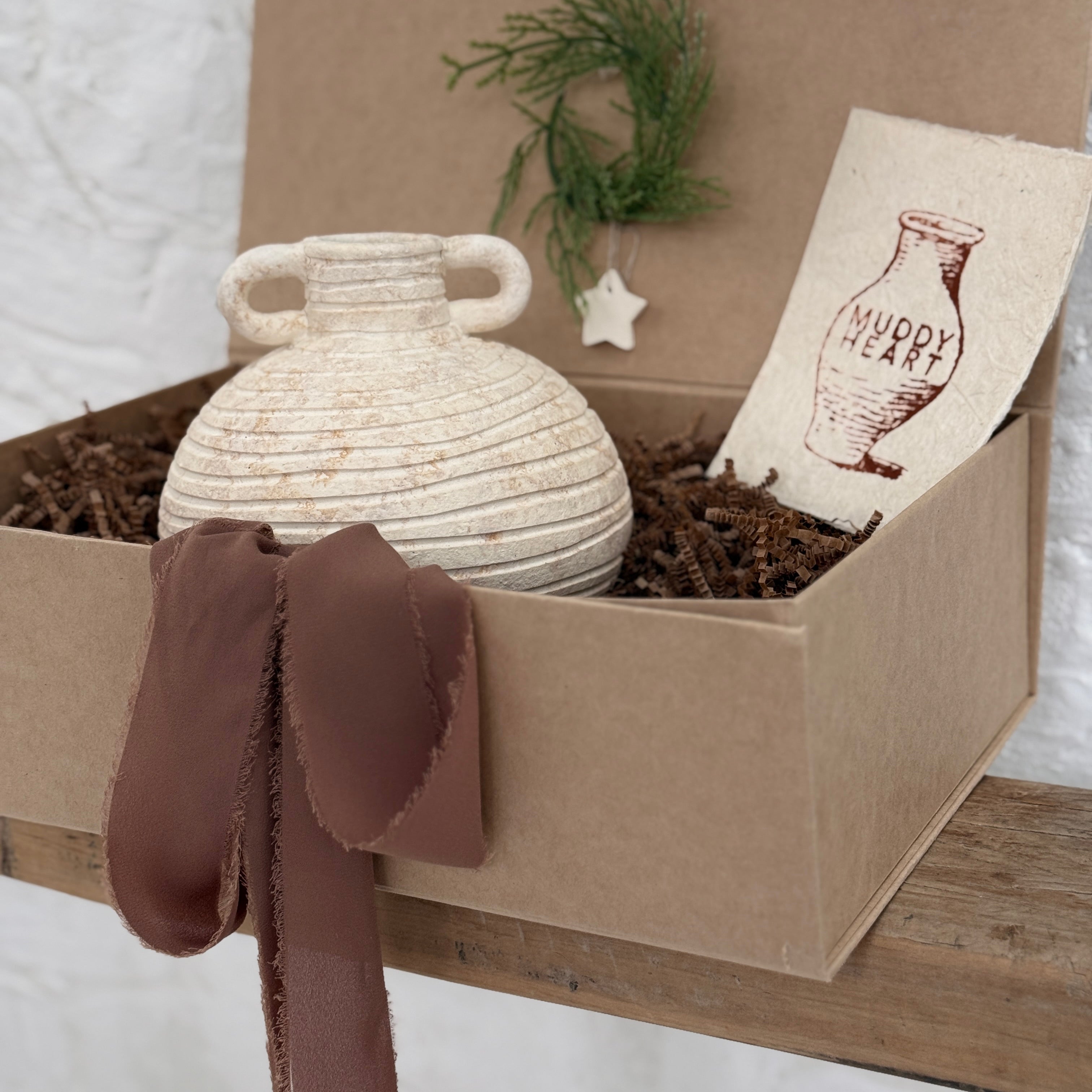Small handmade ceramic vessel with a softly textured neutral finish, styled as a vase and shelf accent.