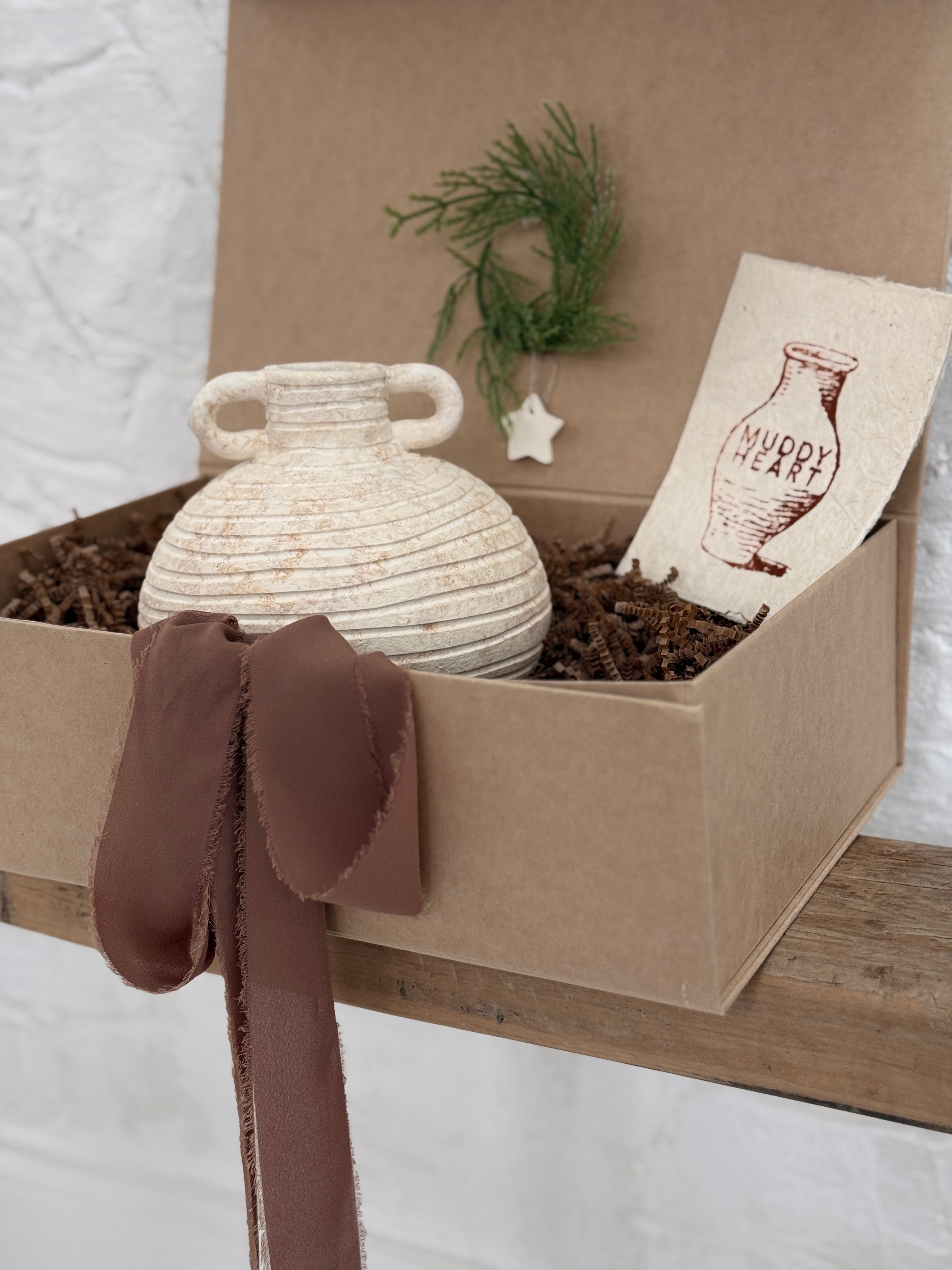 Small handmade ceramic vessel with a softly textured neutral finish, styled as a vase and shelf accent.