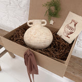 Small handmade ceramic vessel with a softly textured neutral finish, styled as a vase and shelf accent.
