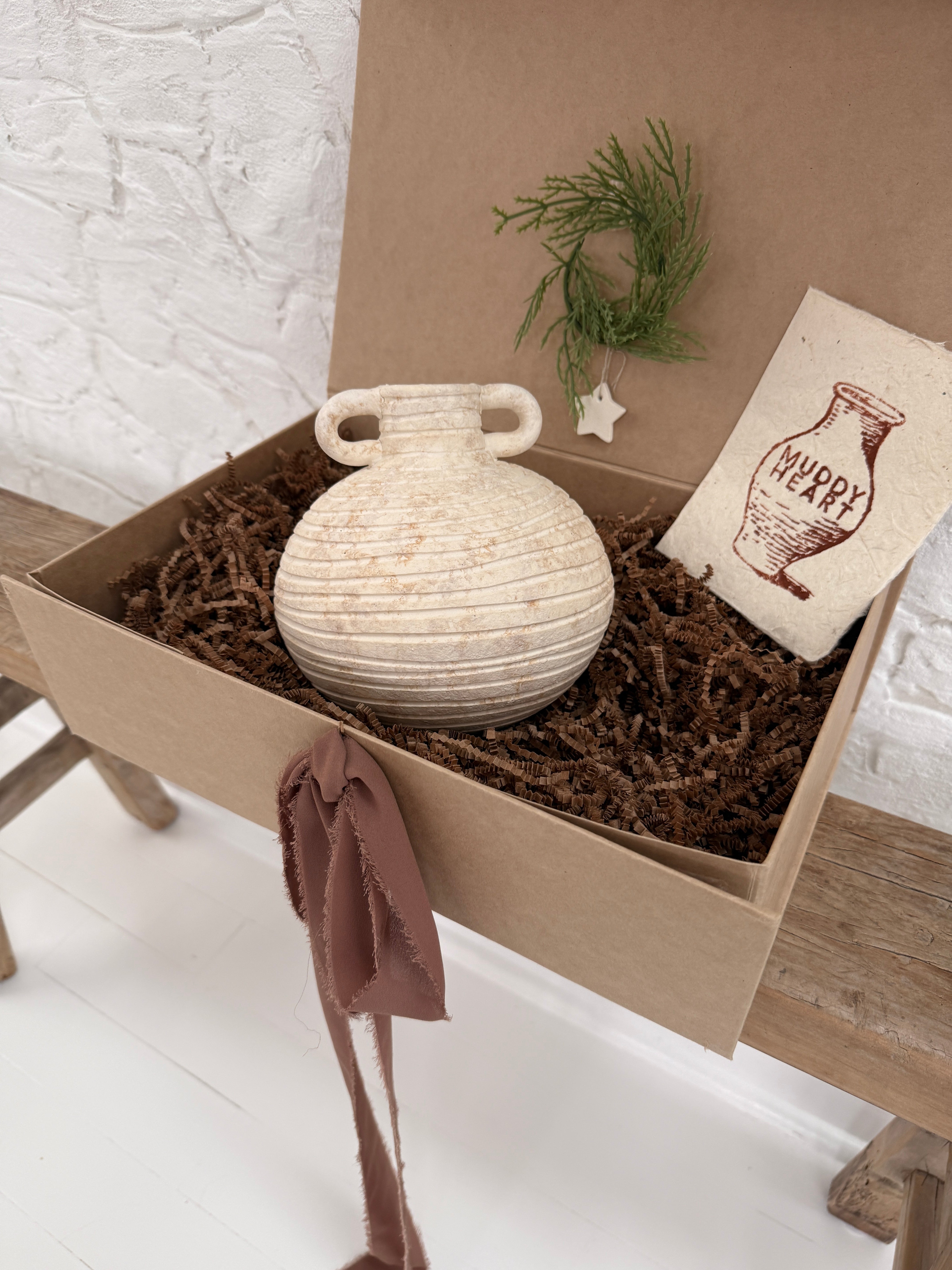 Small handmade ceramic vessel with a softly textured neutral finish, styled as a vase and shelf accent.
