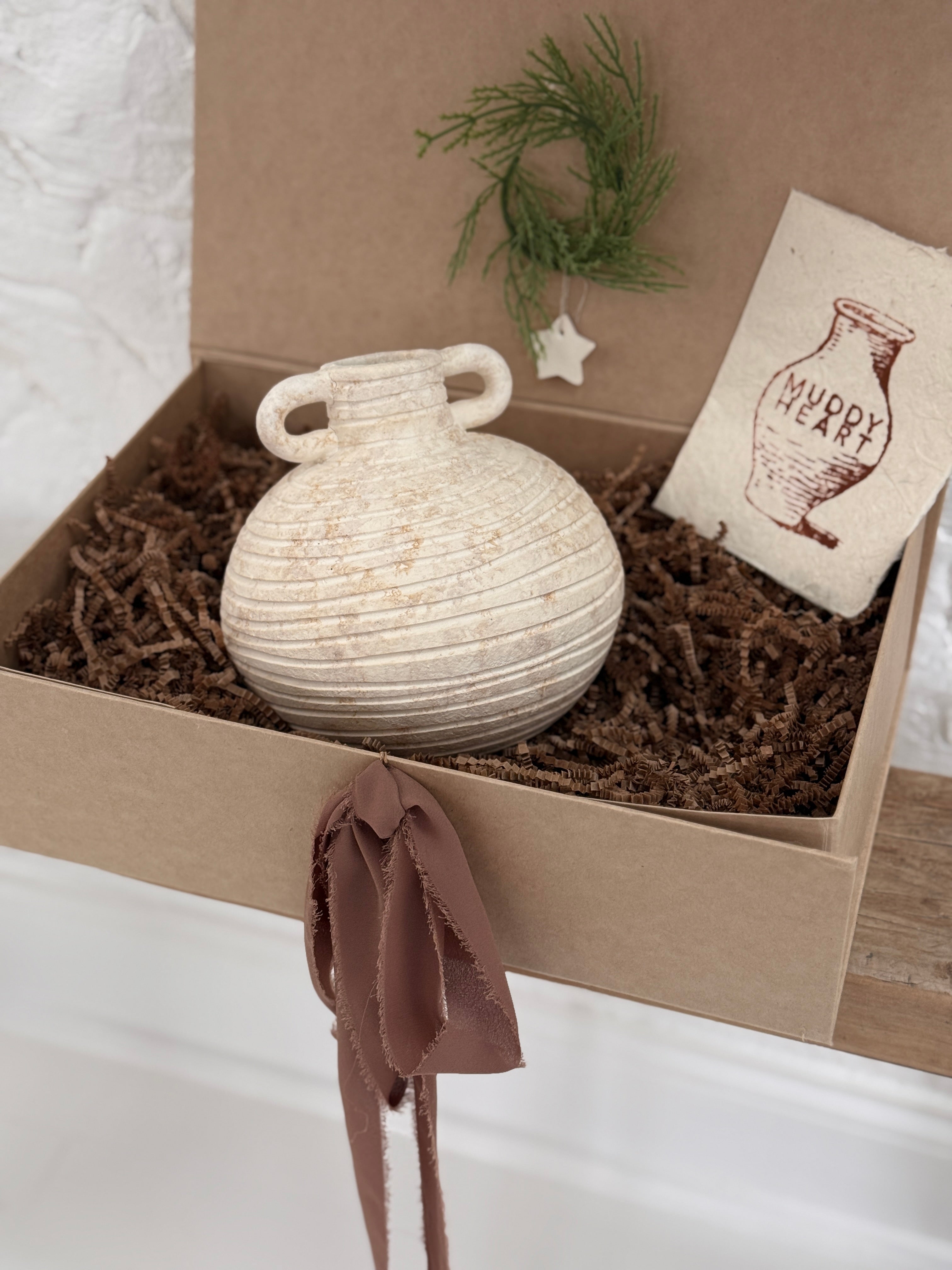 Small handmade ceramic vessel with a softly textured neutral finish, styled as a vase and shelf accent.