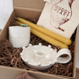 Handmade ceramic candle holder with a pair of beeswax candles and a ceramic match striker, arranged as a gift set.