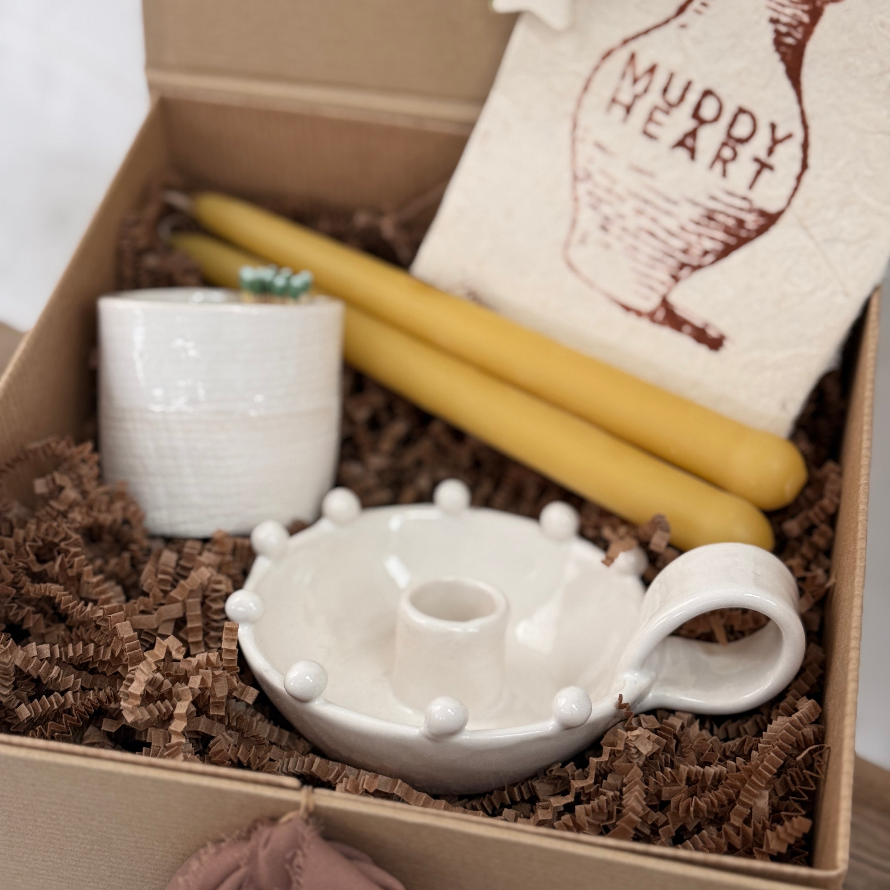 Handmade ceramic candle holder with a pair of beeswax candles and a ceramic match striker, arranged as a gift set.